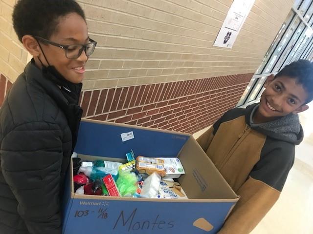 Two students moving a box of collected items
